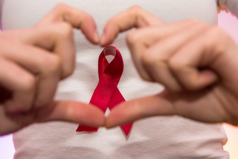 Female hands close up with red ribbon. AIDS company concept. Social advertising